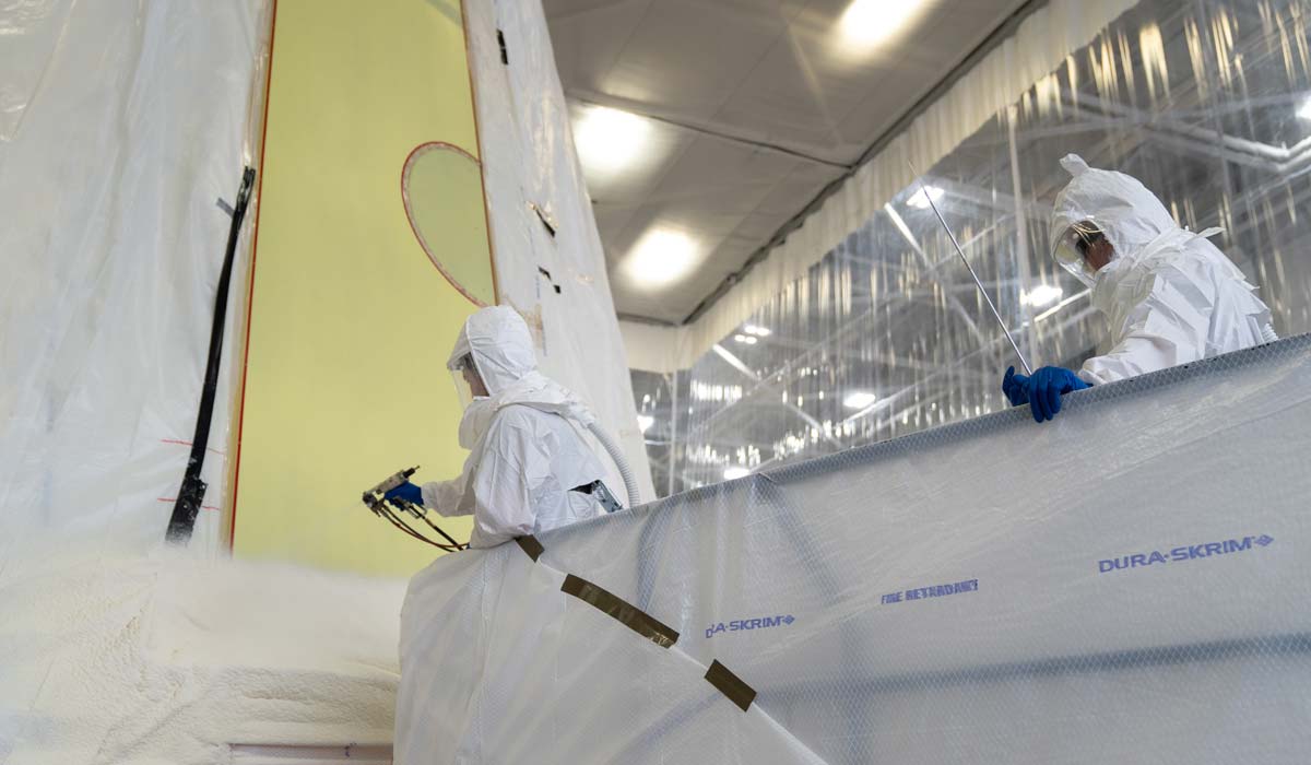 Технические специалисты наносят пену на оборудование лунной ракеты для Artemis III